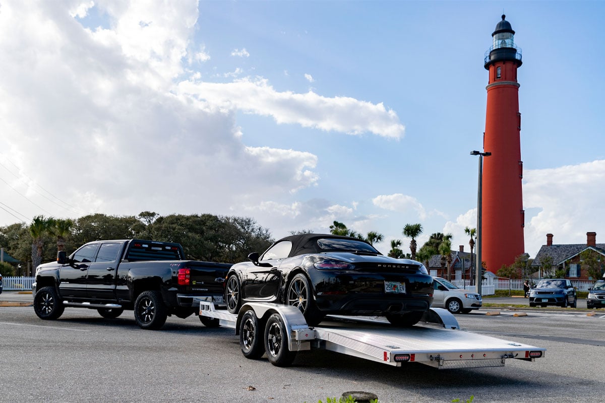 Back View Of Black Truck Hauling Black Car On CargoPro Open Car Hauler