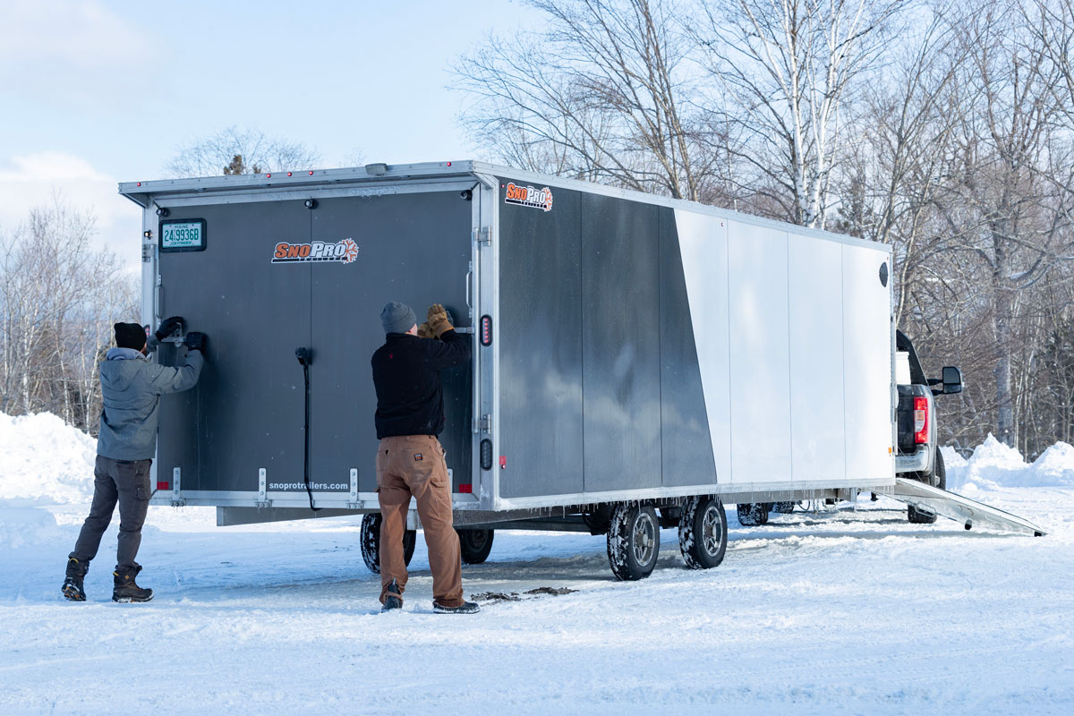 Two Men Opening Rear Ramp On SnoPro Enclosed Deckover 6.5-Height Snow Trailers